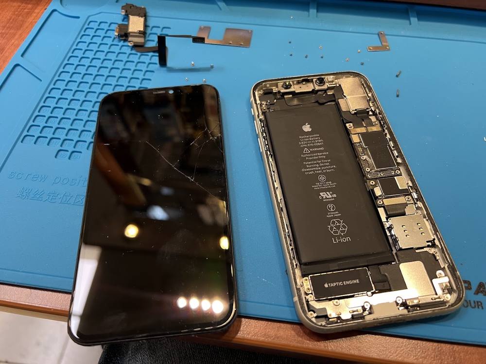 An iPhone opened up on the FIXZONE repair mat, battery showing