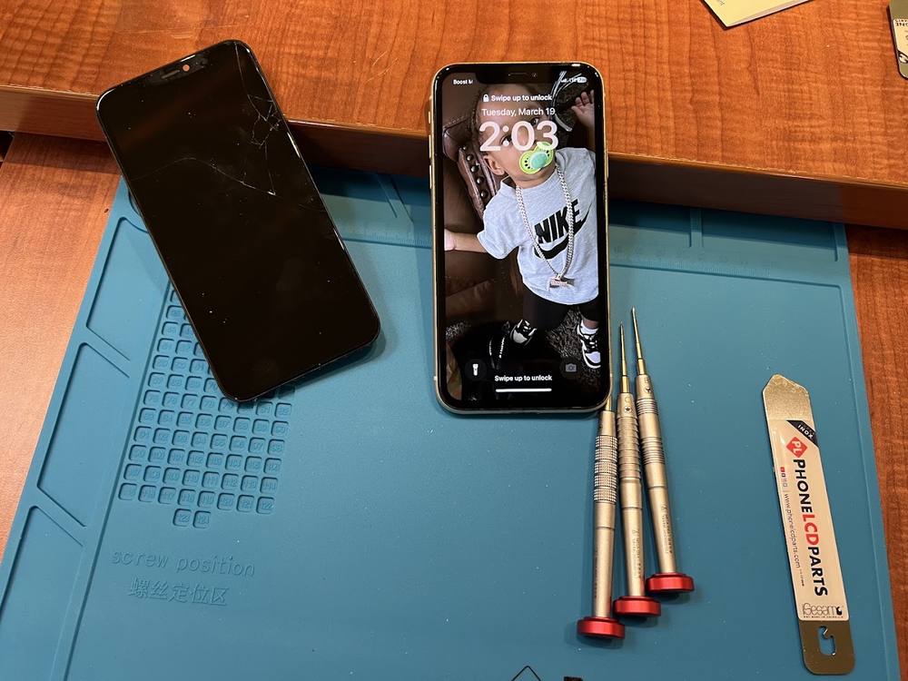 Two iPhones on the FIXZONE repair mat with precision screwdrivers