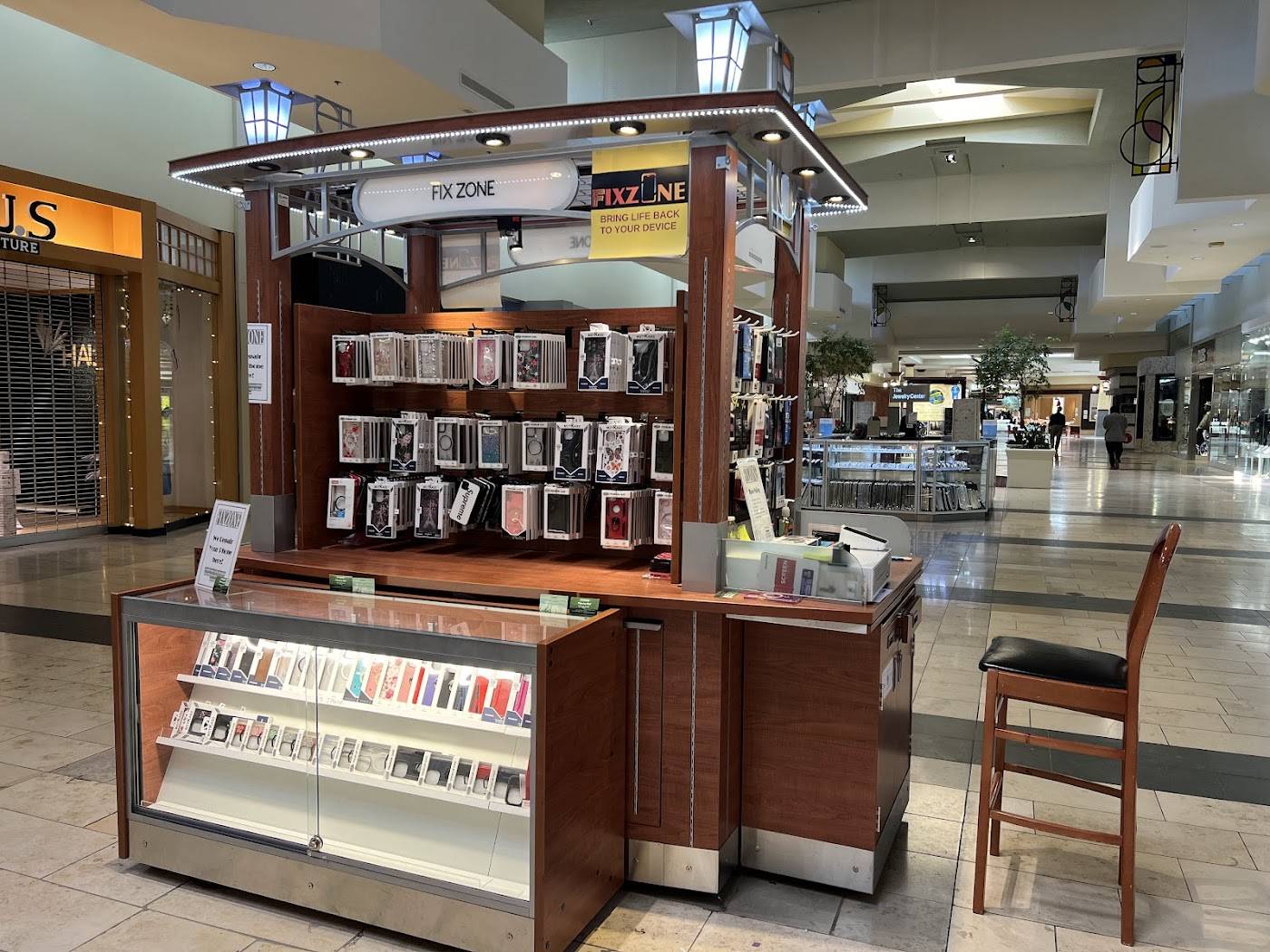 The FIXZONE repair kiosk inside Lansing Mall, walls of phone cases and a glass display counter